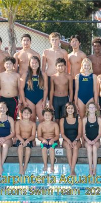 Water polo players stand on bleachers near pool edge for team photo